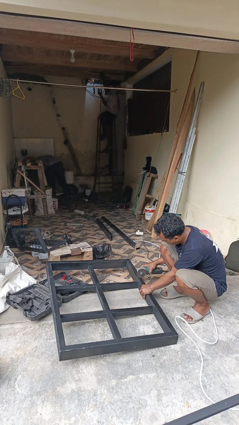 Pekerja merakit rangka besi di lantai sebelum dipasang