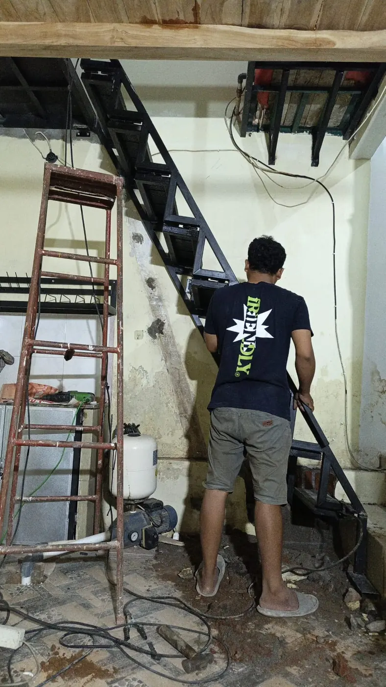 Pekerja memasang struktur baja pada dinding bagian dalam bangunan