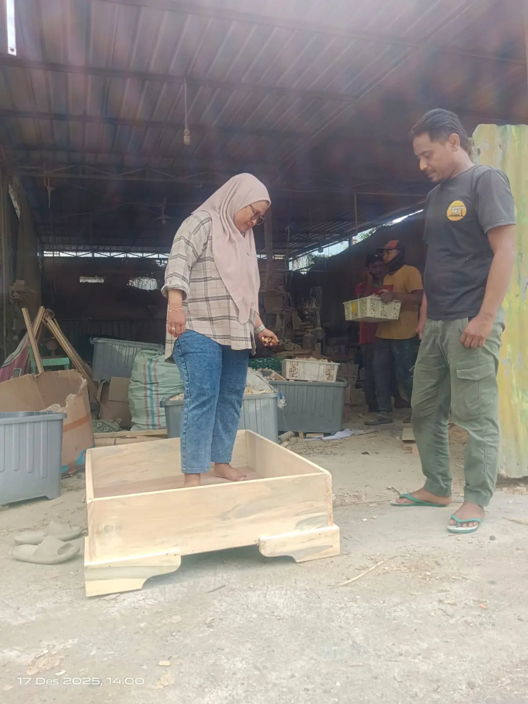Pemesan meninjau boks kayu berukuran besar yang sedang dikerjakan di bengkel