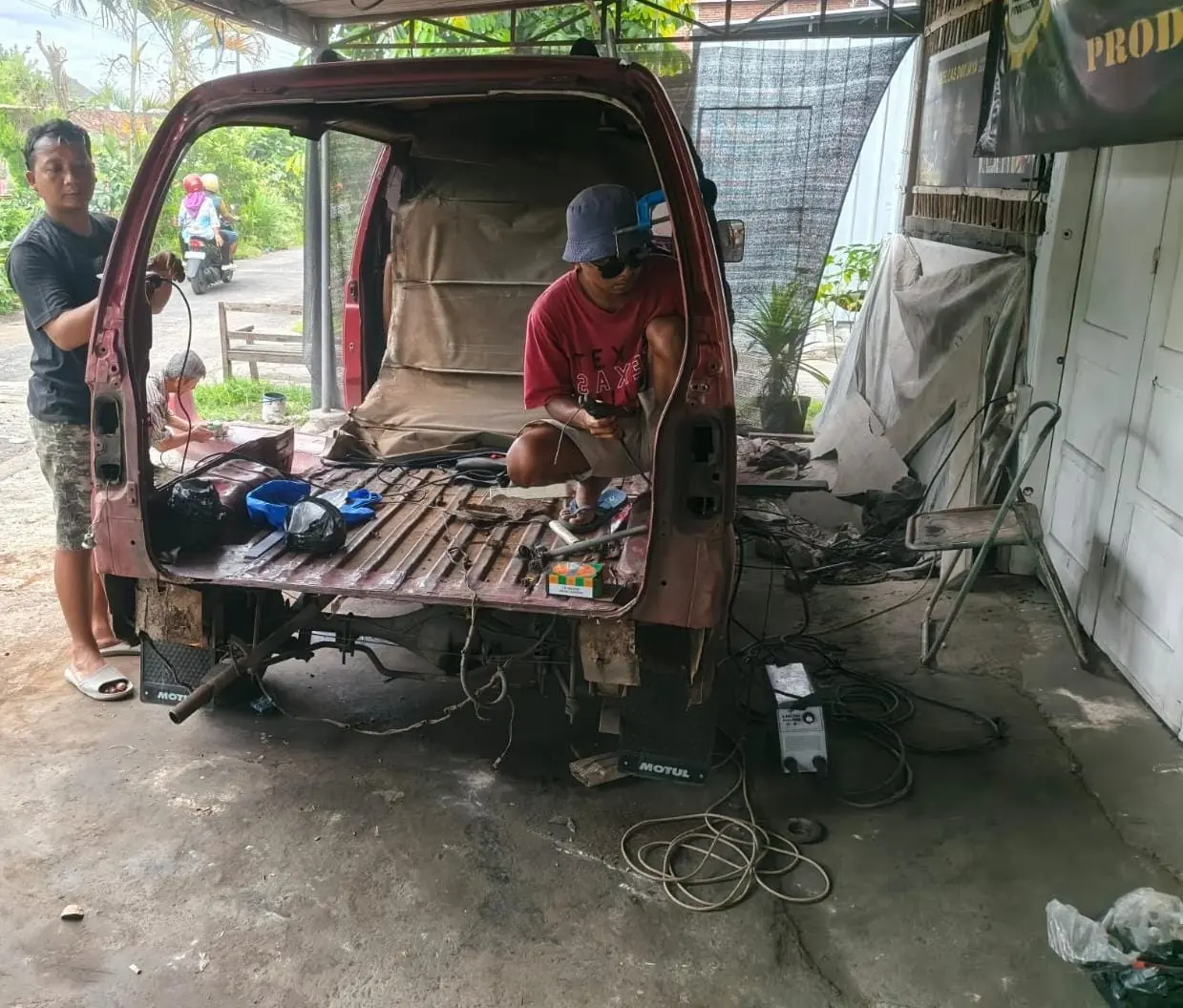 Pekerja mengerjakan rangka lantai kendaraan dari bawah bodi