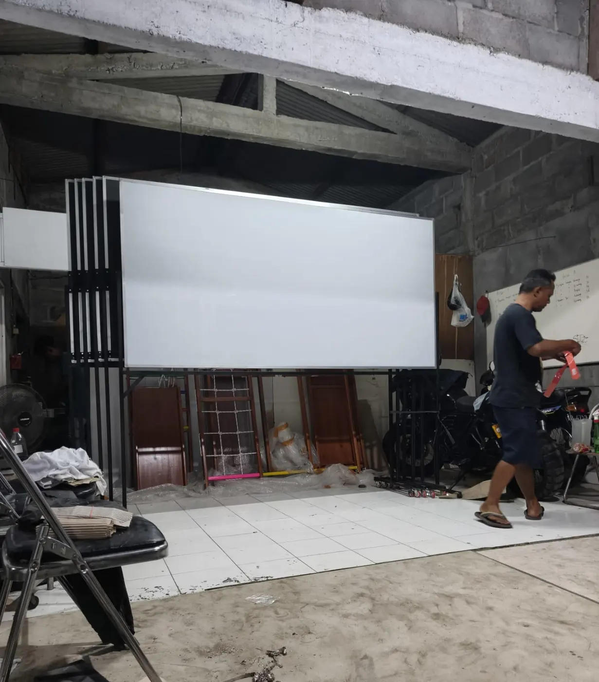 Papan tulis berukuran besar terpasang pada rangka besi di dalam aula