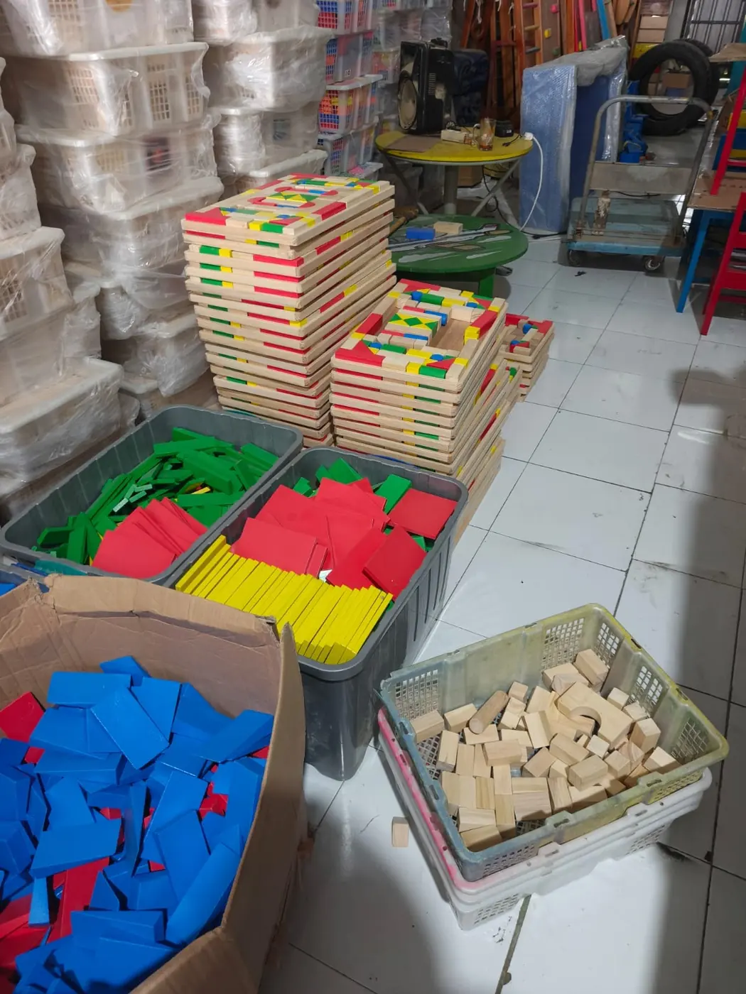 Stok kepingan permainan kayu dan busa berwarna di gudang